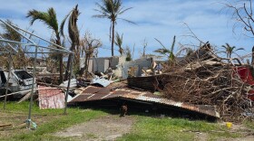 A tin‑and‑wood house lies in ruins after Super Typhoon Bavi’s landfall on Rota on July 6, leaving twisted metal, uprooted trees, and shattered walls in its wake.