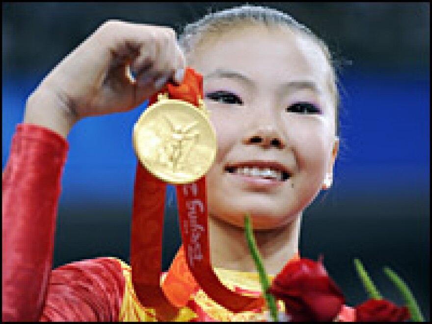 China's He Kexin shows her gold medal after winning the women's uneven bars final of the artistic gymnastics event at the Beijing Olympics.
