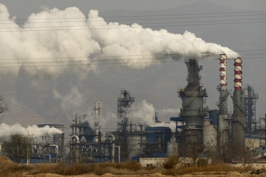 In this Nov. 28, 2019, file photo, smoke and steam rise from a coal processing plant in Hejin in central China's Shanxi Province. Global shoppers face possible shortages of smartphones and other goods ahead of Christmas after power cuts to meet government energy use targets forced Chinese factories to shut down and left some households in the dark. (AP Photo/Olivia Zhang, File)