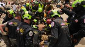 U.S. firefighters from Fairfax County search and rescue team pull a boy from the rubble after rescuing him and his father from a building that collapsed in the earthquakes in La Guaira, Venezuela, Sunday, June 28, 2026.