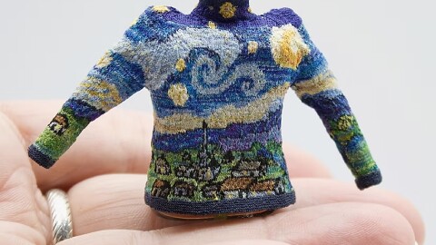 a tiny sweater knit with the pattern of the Van Gough painting Starry Night, sits in a persons hand.