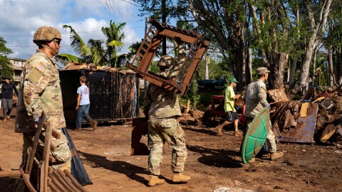 Hawaii National Guard soldiers and volunteers carry flood-damaged debris at a temporary dump site, Tuesday, March 24, 2026, in Haleʻiwa, Hawaiʻi. (AP Photo/Mengshin Lin)