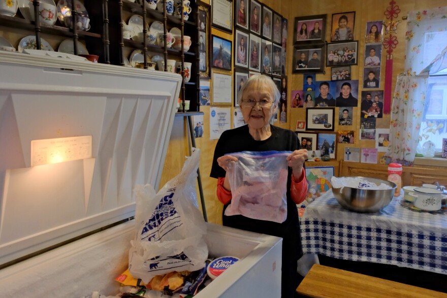 Marie Toolie pulls reindeer meat from her freezer in Savoonga on Sept. 23, 2025.