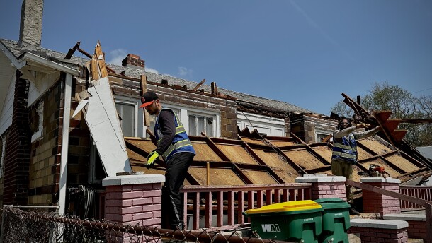 Workers clear debris from a storm-damaged home in kansas city kansas