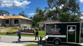 John Doran (left) moving furniture out of the Hands & Feet Ministry trailer into the home of a family in need.