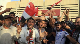 Supporters of Shiite cleric Muqtada al-Sadr raise the Iraqi flags outside parliament in Baghdad's Green Zone on Saturday. Protesters climbed over the blast walls and stormed the Parliament building.