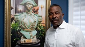 Norwalk Realtor Guy Bocicaut stands next to a photo featuring a bust of Haitian revolutionary leader Sanité Bélair at his offices in Norwalk on July 15, 2025. Bocicaut has called for a series of boycotts by immigrants and is seeking support from immigrant rights advocates.