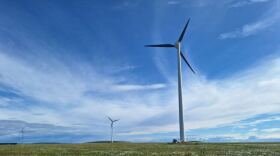 Wind turbines on a green Arctic plain below cloud-streaked skies