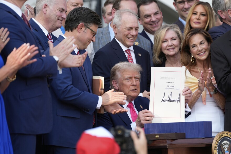 President Donald Trump holds up his signed signature bill of tax breaks and spending cuts at the White House in Washington, Friday, July 4, 2025.