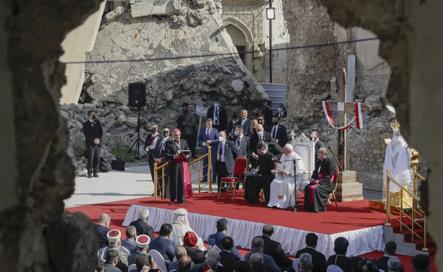 Pope Francis, surrounded by shells of destroyed churches, listens to Archbishop of Mosul Najib Mikhael Moussa during a gathering to pray for the victims of war at Hosh al-Bieaa Church Square, in Mosul.