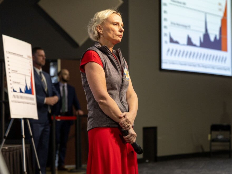 Spartz, a blonde White woman is standing with a microphone on a stage
