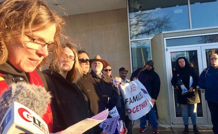 Woman reads from a script outside Bloomington City Hall as other speakers are lined up along her side.