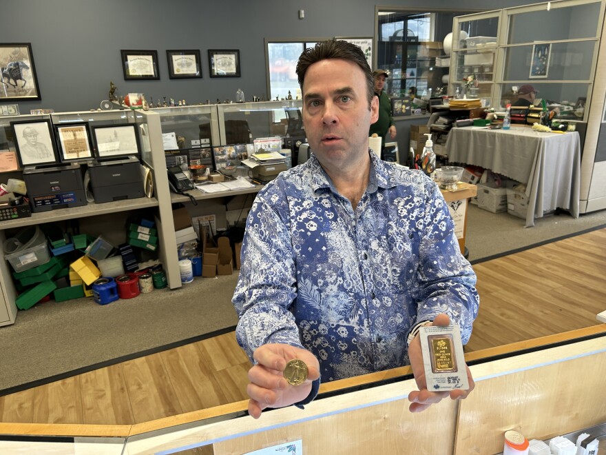 Geoffrey Demis, co-owner of Ferris Coin & Jewelry near Albany, holds up some of the items from his bullion display case at his shop a few miles from the state Capitol.