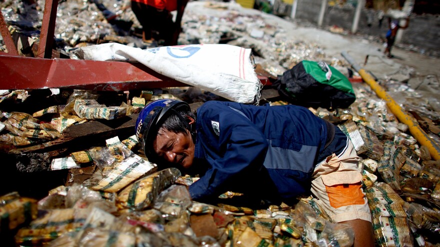 A man dives into the ruins of a cigarette warehouse trying to find dry packs to sell on the streets in San Jose.