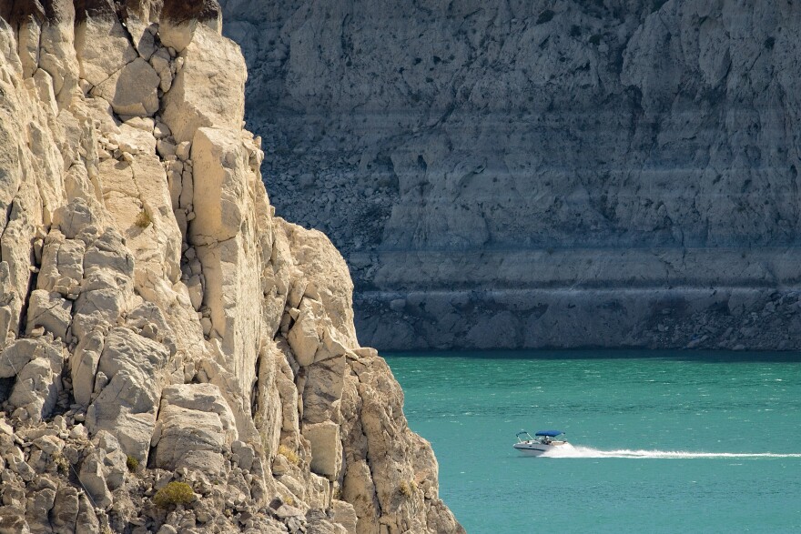 Lake Mead’s light-colored “bathtub ring” of mineral deposits towers above a speeding boat on June 29, 2022, near Hoover Dam.