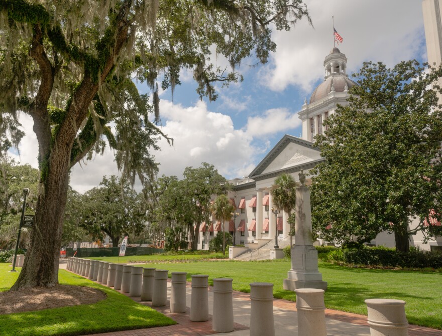 Blue sky behind white clouds over white building with colonnades