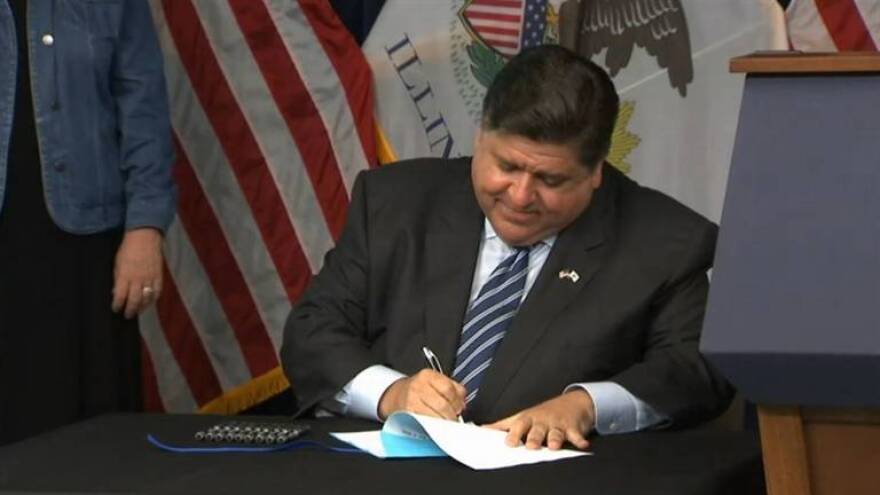 Gov. J.B. Pritzker signs a bill expanding access to family and medical leave benefits to part-time education workers in Illinois during a news conference in Chicago.