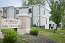 A cluster of two-story wood-frame apartment units sit behind a sign that reads "Stonegate Meadows Information Center."