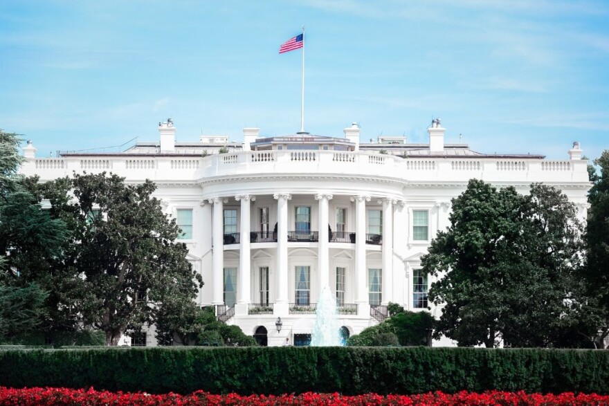 Centered view of the front of the White House with hedge and flowers in foreground