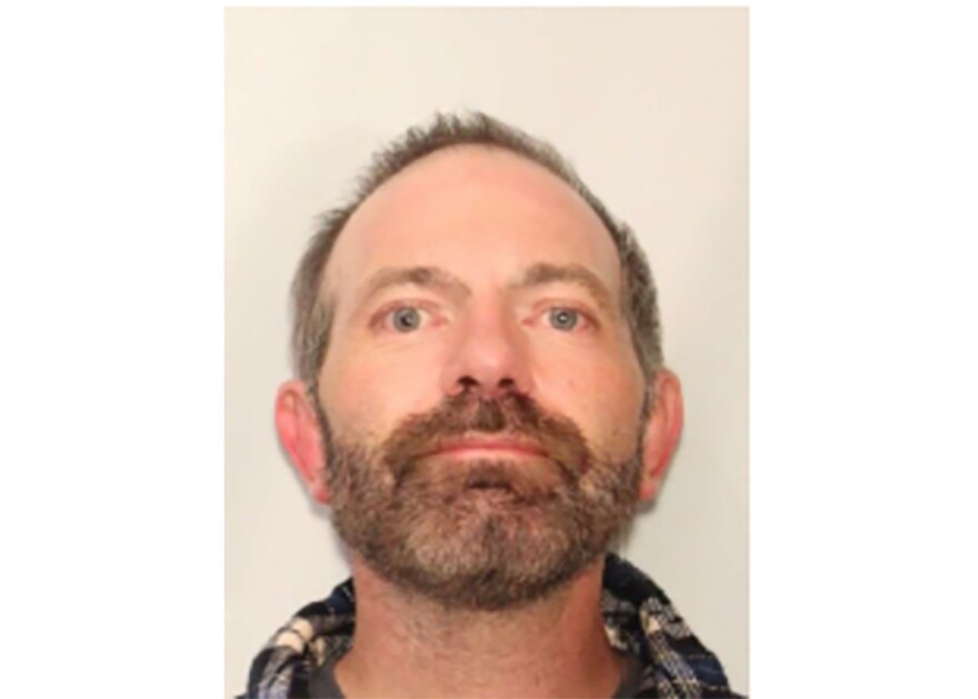 In his mugshot, a man stares straight ahead