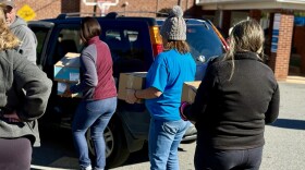 Volunteers load boxes of food into an SUV at a west Charlotte food share for federal workers and SNAP recepients