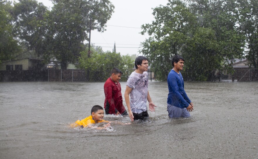 Kids walk — and swim — in the floodwaters in a Houston neighborhood as the rain continues to pour down.