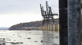pilings along a body water, two container cranes and a cargo ship