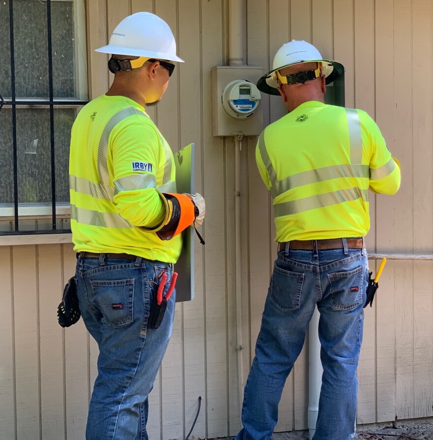Two FPL workers connect lines to a junction box