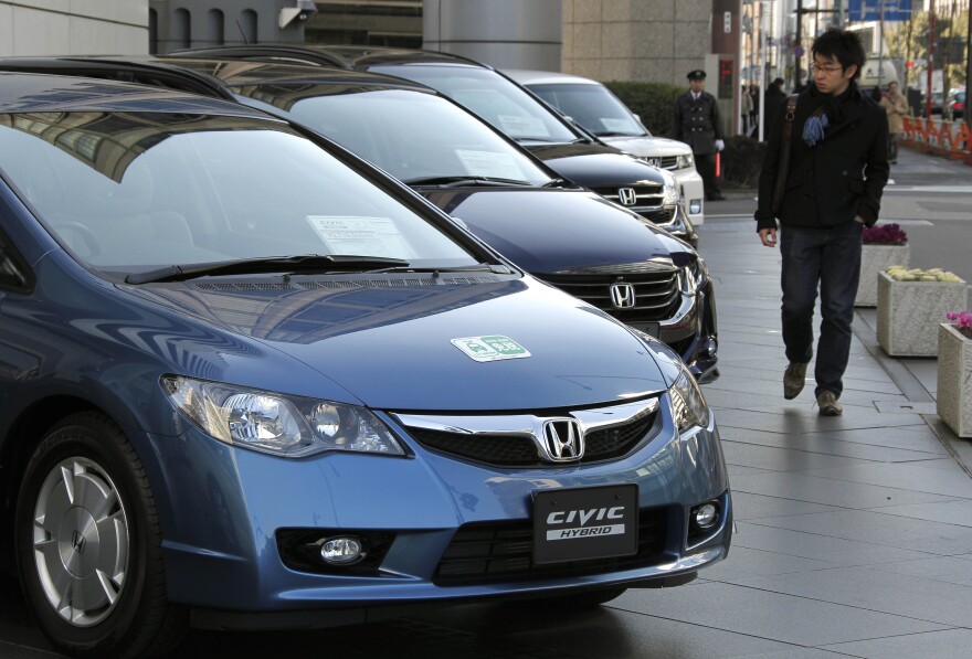 Sayonara, Civic: A man looks at Honda Civic hybrid cars in front of the Japanese automaker's headquarters in Tokyo, Japan, on Jan. 30, 2010.