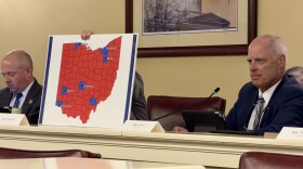 Reps. Brian Stewart (R-Ashville), left, and Adam Bird (R-New Richmond), right, sit in the Joint Committee on Congressional Redistricting, as Nick Santucci (R-Niles) holds a map of counties President Trump won in 2024.