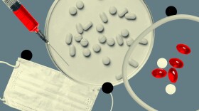 An assortment of pills, a face mask, and a syringe filled with red liquid.