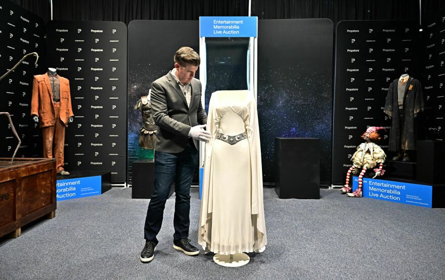 Brandon Alinger, chief operating officer at Propstore, wears white gloves to handle the Princess Leia dress worn by actress Carrie Fisher in the 1977 film <em>Star Wars</em> before it went up for auction in Los Angeles in June.