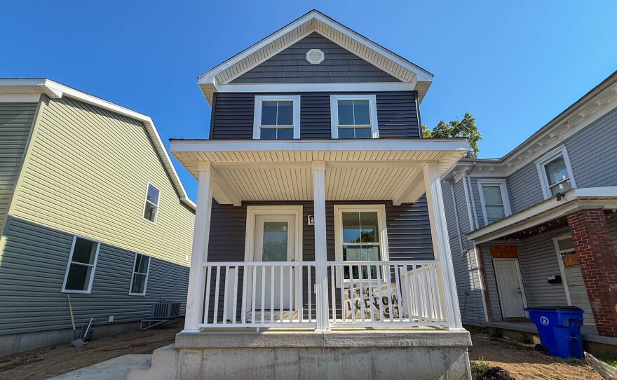 A two story home with a white porch and blue grey vinyl siding.