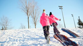 Two people walking with sleds.