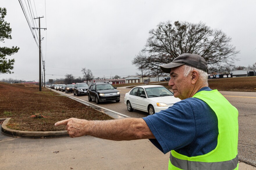 A volunteer guides traffic into the drive-through lanes on Dec. 8, 2022, at the Saint Luke Food Pantry in Tupelo, Mississippi. 