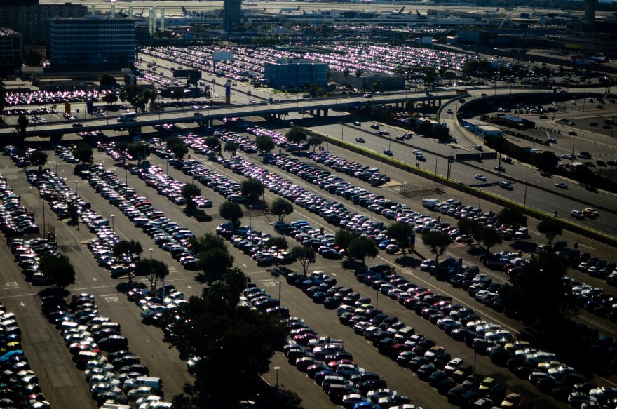 Mass of cars in a parking lot, lined up under the hot sun. 