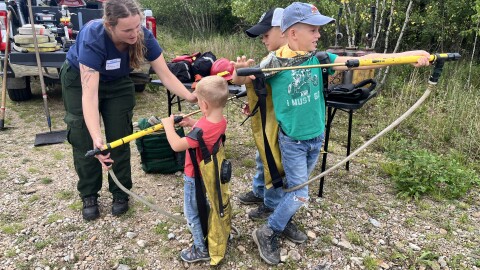 Ashley, from The Nature Conservancy, shows the Jacob, Graham and Jeremy Githens how some of the gear is used in prescribed burns.