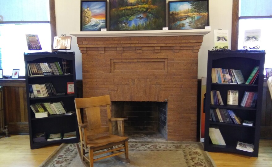 A fireplace with bookshelves on both sides of it and paintings above it.