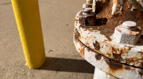 Picture of a white-ish colored gas meter with some corrosion. 