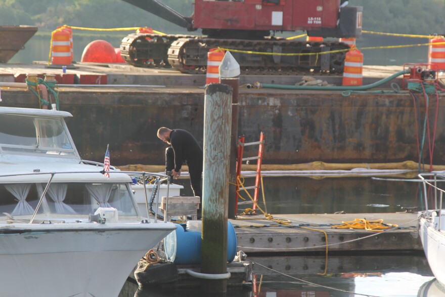 A diver in a black wetsuit on the dock. Billeter Marine's response team included divers to assist with pumping the bilge of the sunken Commando.