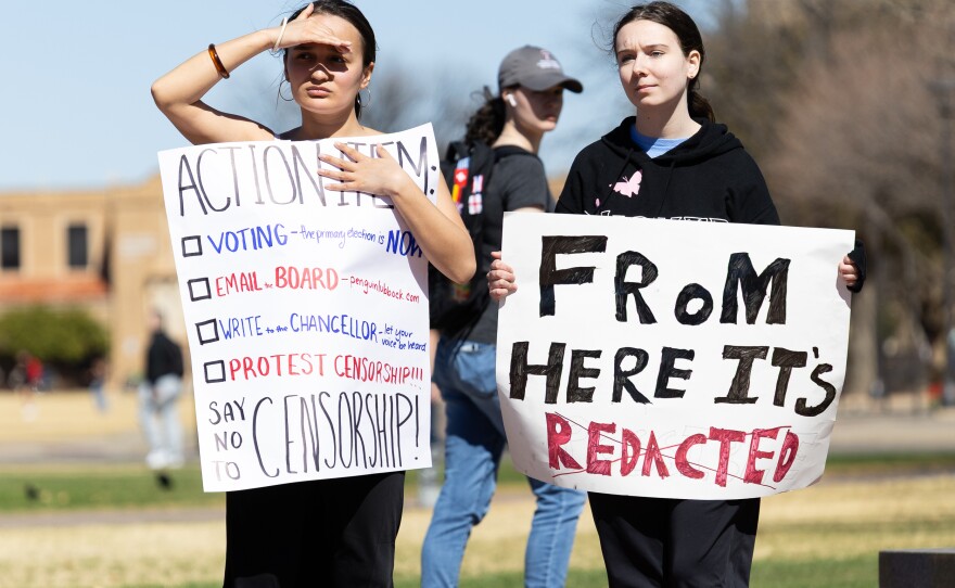 Two students hold signs calling the new review censorship.