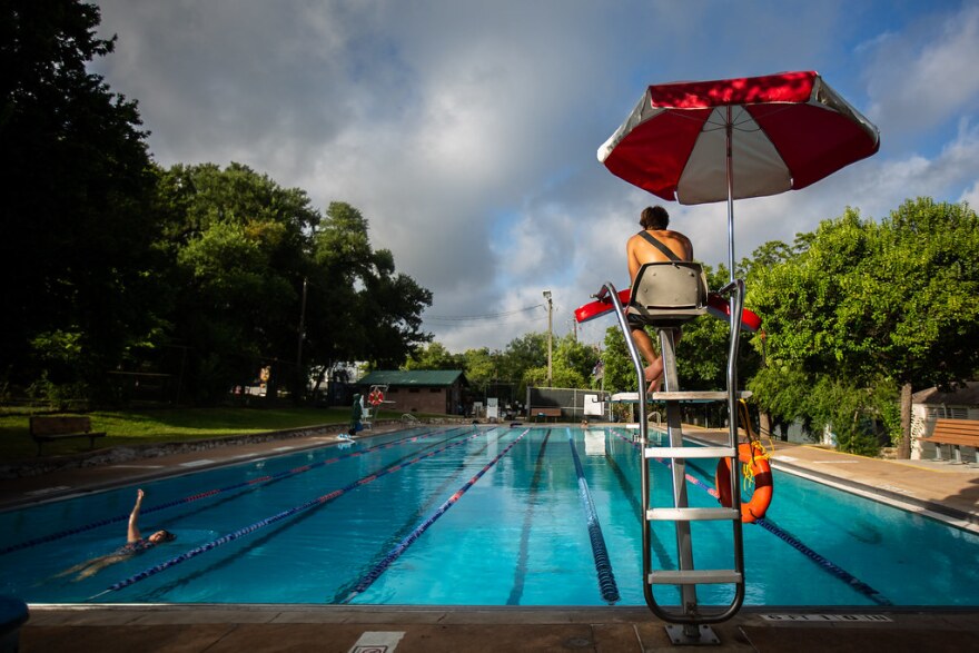 A lifeguard in the lifeguard chair with a big red and white umbrella watches over swimmers at Big Stacy Pool in 2019. 