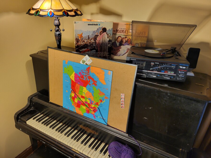  A map of North America propped on a piano, also adorned with a lamp and a record player