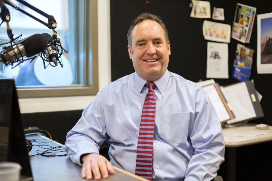 Jake Corman in a shirt and red tie sitting in the WPSU studio near a microphone.