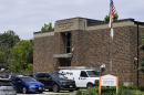 A view of a brick building from the outside. Cars are parked out front.