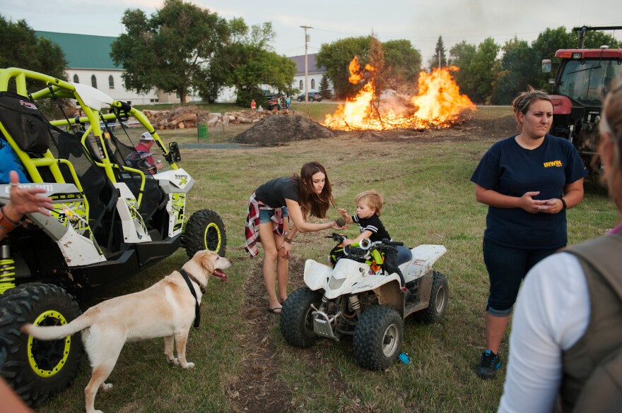 Bailey Morris and her nephew Tucker Lynn play with a dog at a bonfire during Old Settlers Days in Alexander in September. The coals of the bonfire are used to cook about 1,000 pounds of meat to feed celebrants during the annual festival.