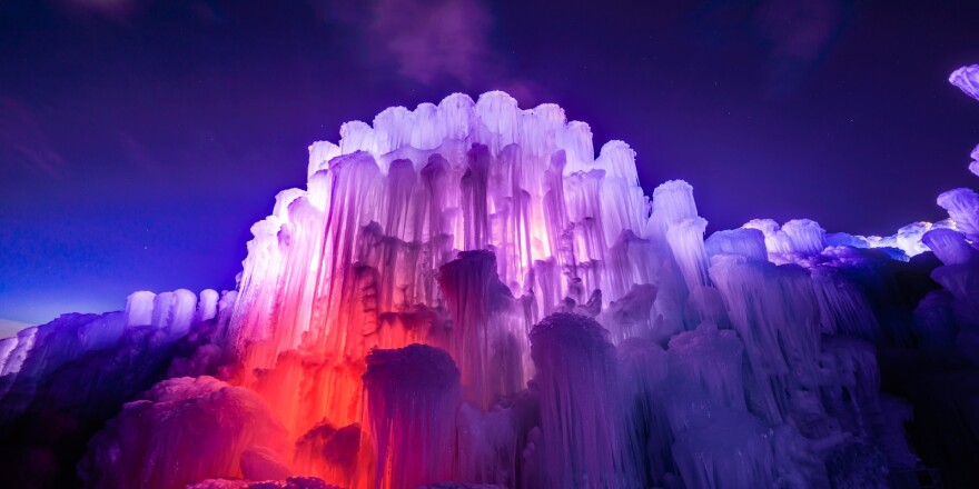 A gigantic ice castle with LED lights inside, giving off purple and pink colors to make the ice glow.