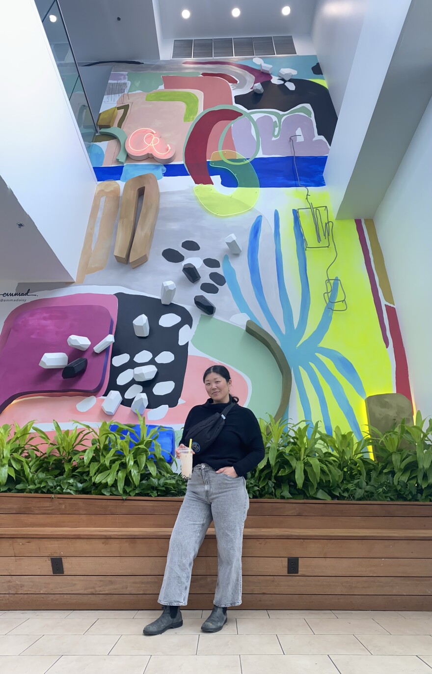 Emma Daisy poses with her abstract mural inside the rotunda of Bayshore Mall in Glendale.