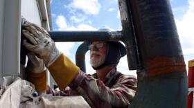 A man in a hard hat works on a building.