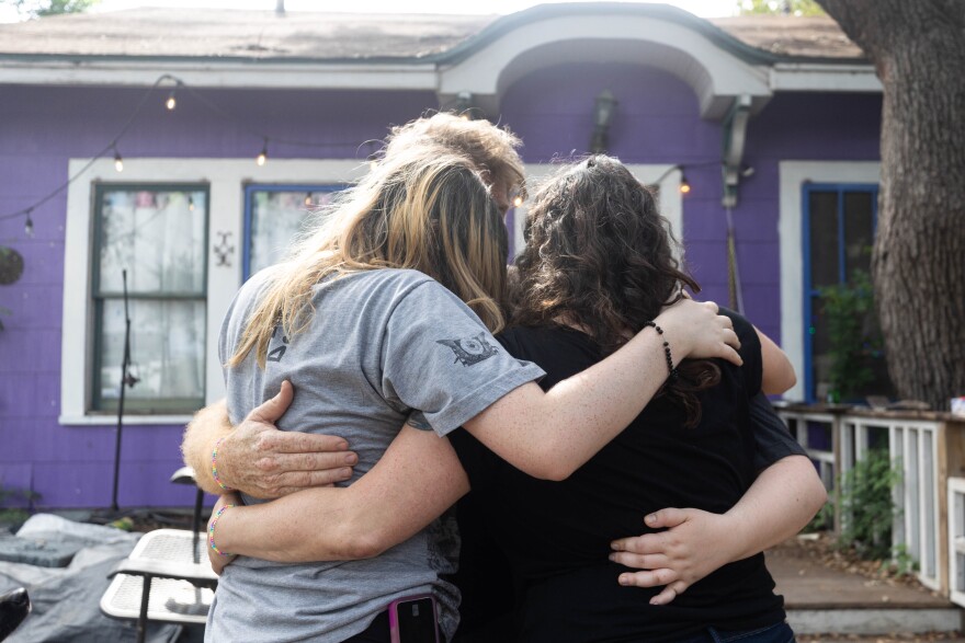 Luna's family hugging infront of their purple home on May 29, 2023. Luna's familys face is hidden to stay anonymous for their family's safety. Patricia Lim/KUT